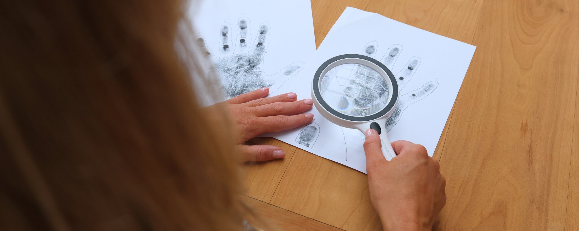 vrouw bekijkt handafdruk met loep